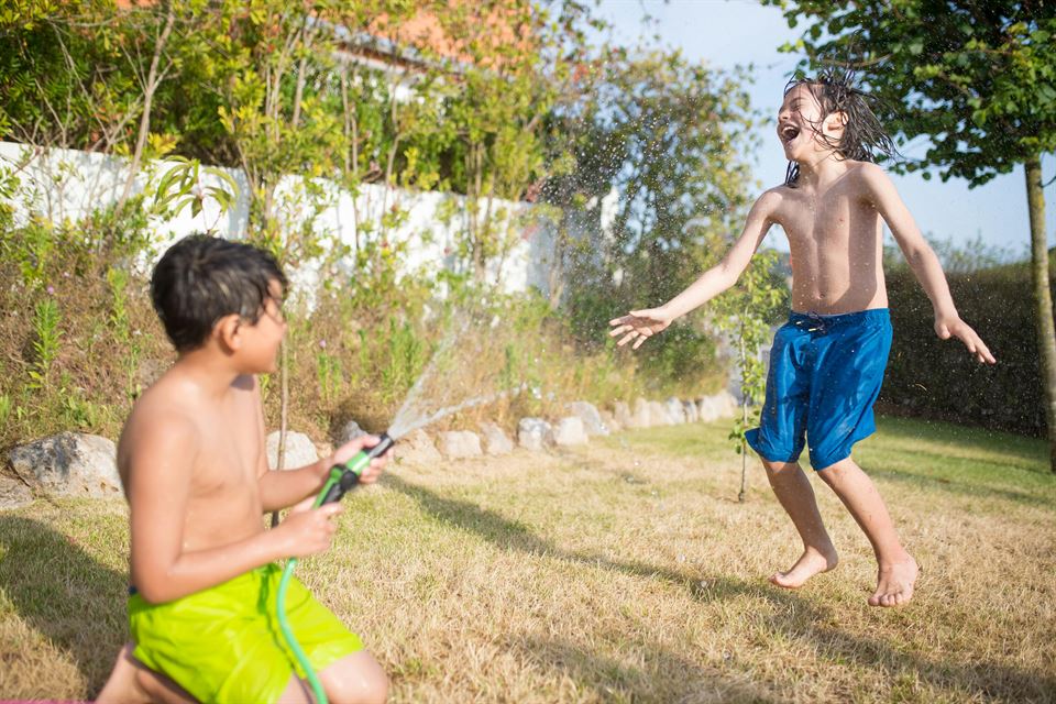 niños-jugando-manguera-agua-jardin-vivienda-vacacional-una-ventajas-del-alquiler-vacacional-sobre-el-hotel