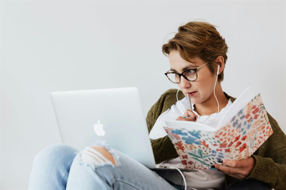mujer-mira-ordenador-portatil-y-escribe-cuaderno