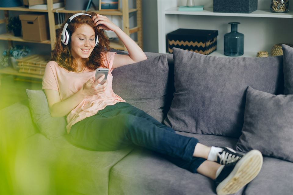 mujer-con-cascos-y-movil-sentada-sofa